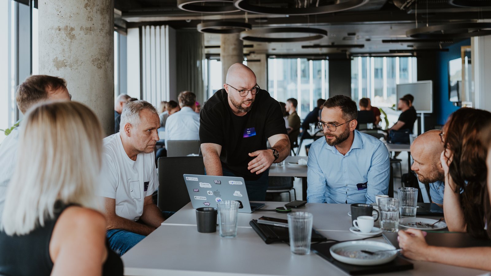 Tomáš Paulus radí skupině u stolu s laptopy na Vibe Coding Summer 2026