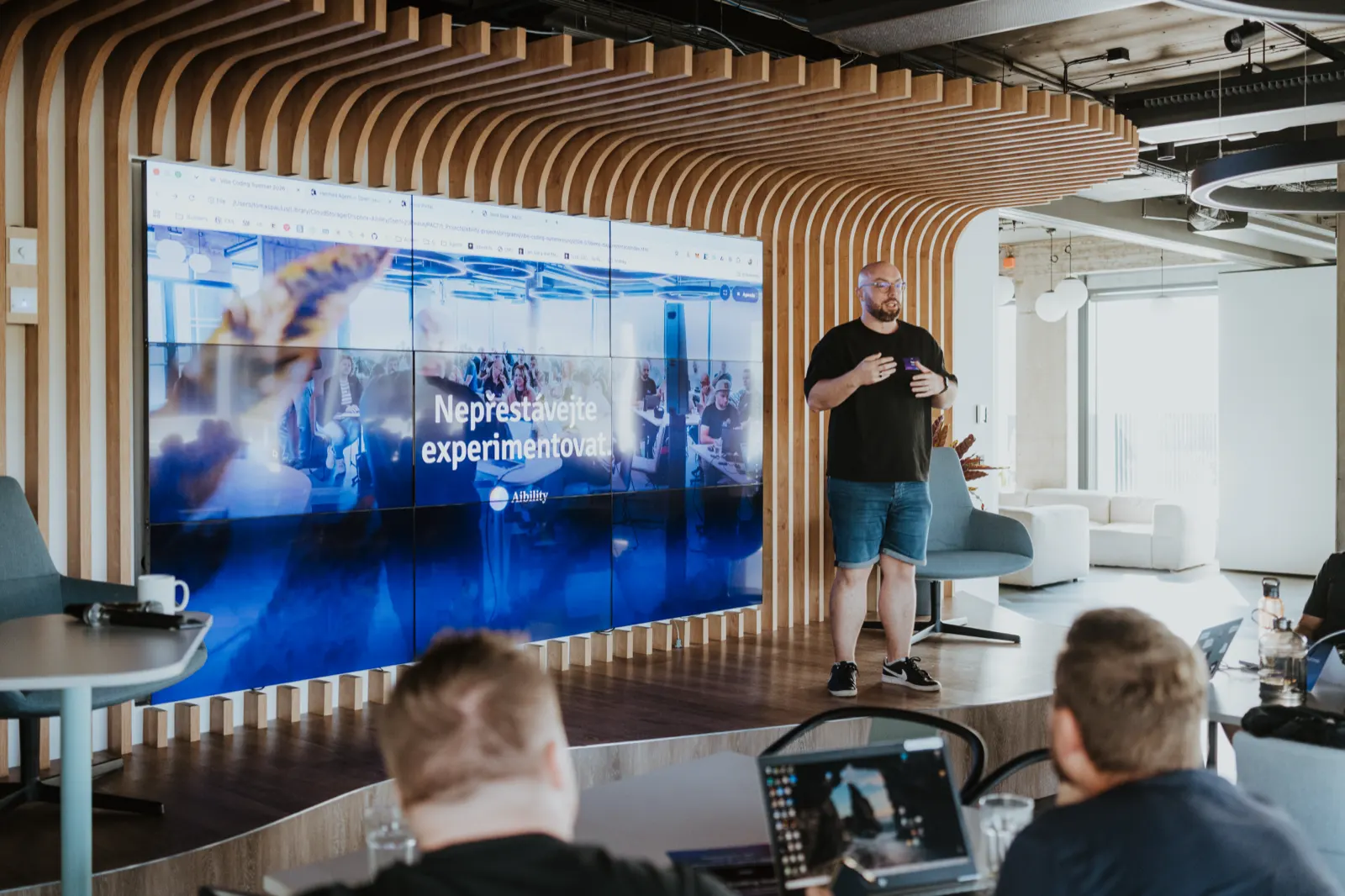 Tým Aibility na pódiu Demo Day, na obrazovce nápis Nepřestávejte experimentovat
